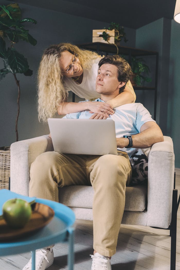 Young couple bonding at home while using a laptop, capturing warmth and togetherness.